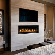 a bedroom with a bed, television and fireplace in the corner near a large window