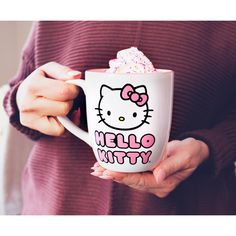 a woman holding a hello kitty coffee mug