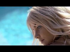 a woman with blonde hair and blue eyes looks off into the distance while standing in front of a pool