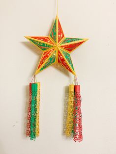 an origami star hanging on the wall next to two small red and green decorations