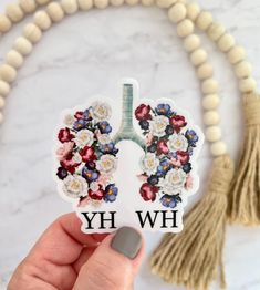 a person holding up a sticker with the words hwh on it and flowers