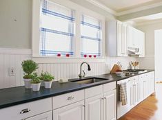 a kitchen with white cabinets, black counter tops and wooden floors is pictured in this image