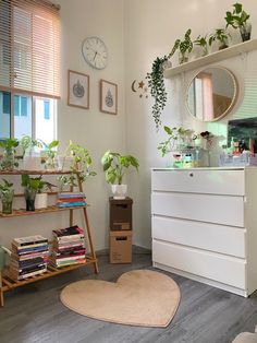 a room filled with lots of plants next to a white dresser and window sill