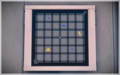 a game board with yellow and blue squares on it's sides, in front of a gray wall