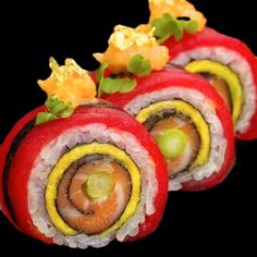 several sushi rolls are arranged on a black plate