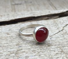 A lovely blood red round carnelian has been set in sterling silver with a handmade ring band from sterling silver half dome wire. The carnelian is 10mm in size and has a deep red color to it. A dark patina or oxidized finish has been applied to darken the silver which enhances the bright blood red of the carnelian. Made to order! Choose your size and finish. Red Moonstone Ring For Anniversary, Red Moonstone Anniversary Ring, Handmade Oval Carnelian Ring, Carnelian Ruby Ring With Oval Cabochon For Gift, Elegant Silver Carnelian Ring, Traditional Red Carnelian Ring, Red Cabochon Ruby Ring, Silver Carnelian Ring Jewelry, Carnelian Cabochon Ring