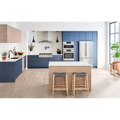 a modern kitchen with blue cabinets and white counter tops, wooden stools, and potted plants