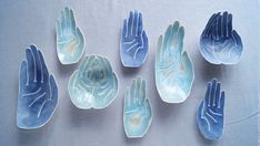 six blue hand - shaped dishes are shown on a white tablecloth, and one has five hands in the middle