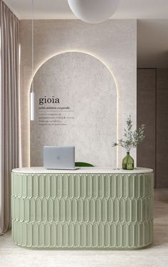 a green reception table with a laptop on it in front of a white wall and window