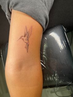 a small tattoo on the arm of a woman with a hummingbird in it's left arm