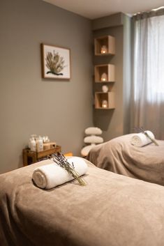 two beds in a room with towels and candles on the wall next to each other