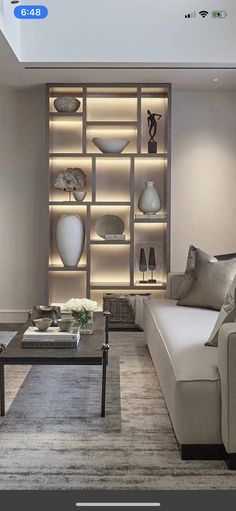 a living room filled with lots of furniture next to a wall mounted book shelf covered in vases