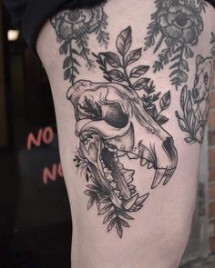 a black and white photo of a skull with flowers on it's side thigh