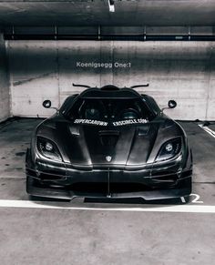 a black sports car is parked in a parking garage with the words koenigeseg one1 on it