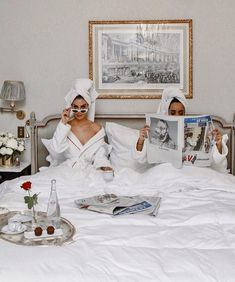 two women in bathrobes reading magazines on a bed