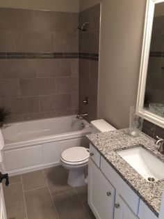 a white toilet sitting next to a bath tub in a bathroom under a mirror above a sink