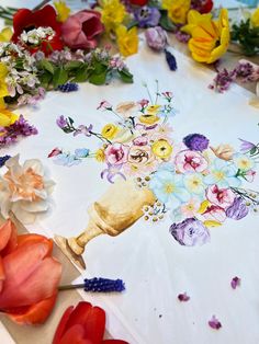 a table topped with lots of flowers on top of a white table covered in paper