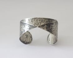 Handcrafted sterling silver cuff bracelet for women or men.   This cuff bracelet has been folded to give it a unique look. The cuff bracelet has a hammered and oxidized surface finish.  The oxidation has been partially removed from the high spots to bring out the hammered details The cuff bracelet is made for a 6 inch (15.25 cm) wrist, contact me if you would like me to custom make this cuff in another size. The width of the bracelet is 1 inch (25.4 mm) at the ends and 0.5 inch in the middle (12 Modern Hand-cast Cuff Bracelet As Gift, Hand Forged Silver Cuff Bracelets, Hand Forged Silver Cuff Bracelet, Origami Folding, Handcrafted Bracelets, Sterling Silver Cuff Bracelet, Celtic Designs, Sterling Silver Cuff, Hammered Silver