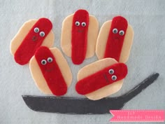 four hotdogs with googly eyes are on a piece of felt