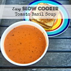 a bowl of tomato basil soup next to a plate with grilled cheese on it