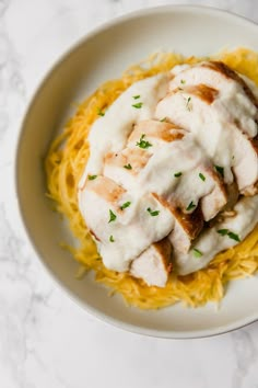 a white plate topped with pasta and chicken covered in gravy