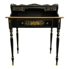 an antique black and gold painted desk with flowers on the front, drawers and legs