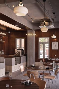 an empty restaurant with tables and chairs in the center, along with lights hanging from the ceiling