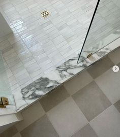 a tiled bathroom with a glass shower door and marble tile flooring on the walls