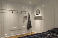 a bedroom with two coats hanging on the hooks and a bed in front of it