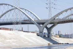 a bridge over water with power lines above it and people in the water below them