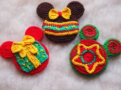 three crocheted mickey mouse ornaments on a white surface