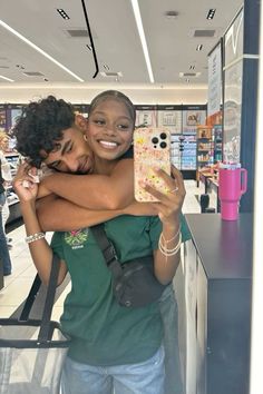 two women hugging each other in front of a store counter and one is holding her phone