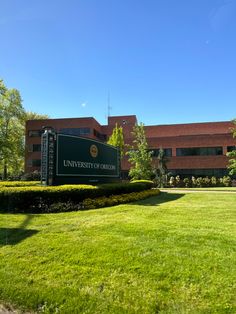 the university of oregon campus sign in front of a building with green grass and bushes