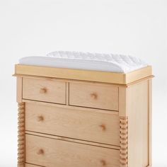 a wooden dresser with two drawers and a mattress on top of it, against a white background