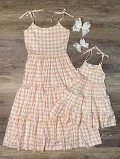 Create a picture-perfect mommy and me moment with our delightful "Mommy and Me" white and taupe gingham ruffle matching dresses! These charming tank style dresses are designed with tie adjustable straps, allowing for a perfect fit for both moms and their little girls. The dresses feature a classic and timeless taupe and white gingham plaid pattern, adding a touch of vintage-inspired charm. The three-tiered layers create a whimsical and feminine silhouette, perfect for twirling and capturing prec Mom Daughter Matching Dresses Mommy And Me, Mother Daughter Fashion Matching Outfits Mommy And Me, Matching Dresses For Mother And Daughter Summer, Mom And Daughter Matching Dresses Summer, Mom And Daughter Matching Dresses Spring, Mommy Daughter Dresses, Mommy Daughter Outfits, Mother Daughter Fashion, Girls Boutique Clothing