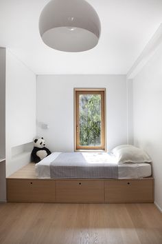 a bed sitting under a window in a bedroom next to a stuffed panda bear on the floor