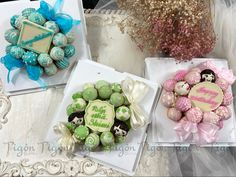 three decorated cookies are on display in white trays with blue bows and ribbons around them