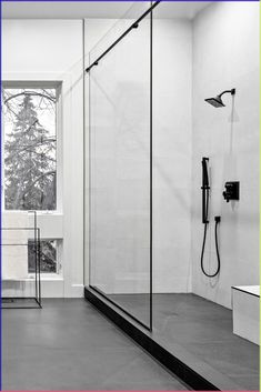 a black and white photo of a bathroom with a shower head, toilet and window