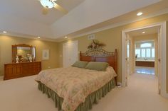 a bedroom with a bed, dresser and mirror on the wall next to an open door