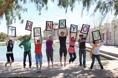 a group of people holding up signs in front of a water fountain with the words thank you written on them