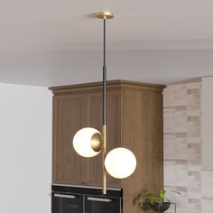 two lights hanging from the ceiling above a stove top oven in a kitchen with wooden cabinets