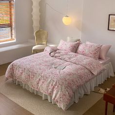 a bed with pink and white comforter in a bedroom next to a window,