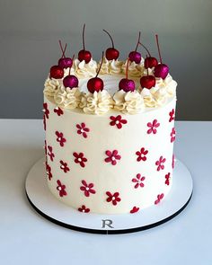 a white cake with red flowers and cherries on top is shown in an instagram