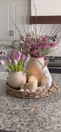 a vase with flowers and candles sitting on a kitchen counter next to a candle holder