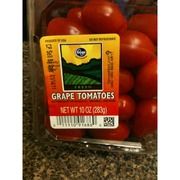 some tomatoes are in a plastic container on the counter top with a label that says grape tomatoes