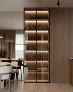 a dining room and kitchen area in an apartment with wood paneling, glass sliding doors, and white chairs