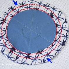 a circular piece of fabric with red and blue thread in the middle, on top of a white plate