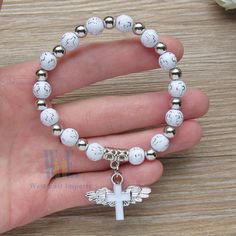 "These Wing of Angel bracelets are absolutely stunning Favors for baptism. 12 Pcs WHITE ANGEL CHARM BRACELET - A meaningful and useful favor for Baptism and religious events The Wings of angel adorn with a beautiful enamel cross Each bracelet comes with WHITE ORGANZA GIFT BAG. Stretchy bracelet fits youth and adult wrists. Wood bead size 8mm, Charm size: .75\" x 1\", fits youth & adult" Adjustable Hypoallergenic White Charm Bracelet, White Adjustable Bracelet For Confirmation, Adjustable White Bracelet For Confirmation, White Spiritual Jewelry For Confirmation, Spiritual White Jewelry For Confirmation, Adjustable White Rosary Bracelet For Confirmation, Personalized White Beaded Bracelets For First Communion, Personalized White Beaded Bracelets For Baptism, Personalized White Bracelets For Confirmation