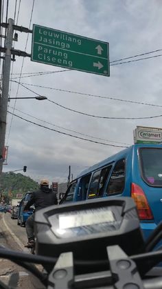 there is a blue van driving down the street next to a green and white sign