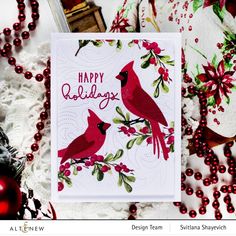 a christmas card with two red birds on it, surrounded by holiday decorations and ornaments